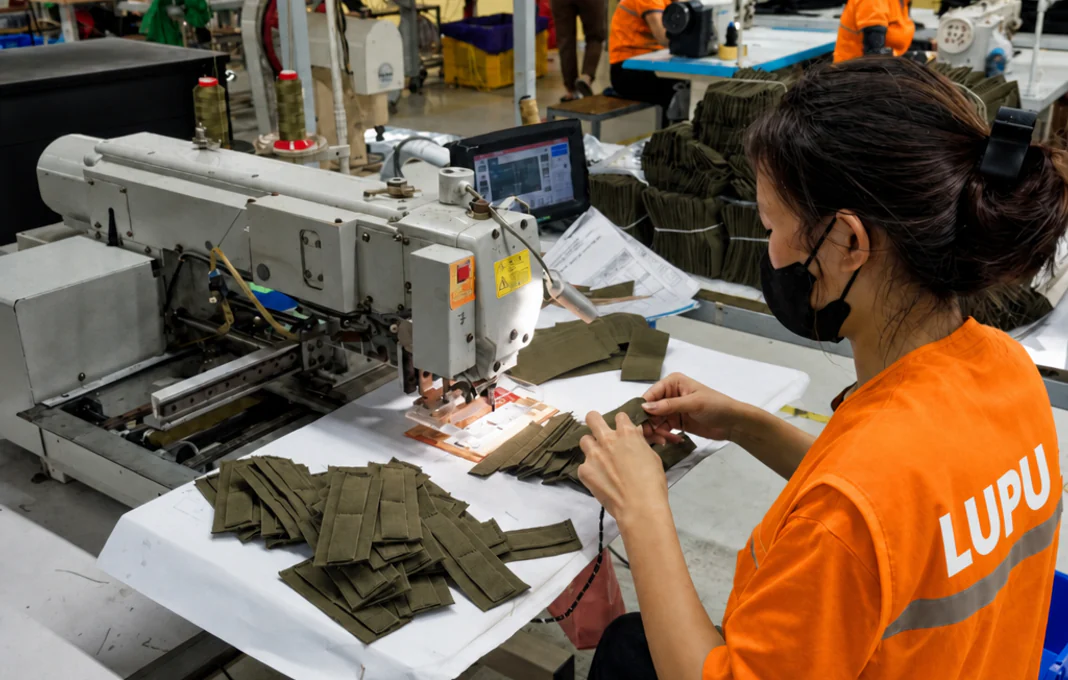 Woker sewing webbing in factory workshop